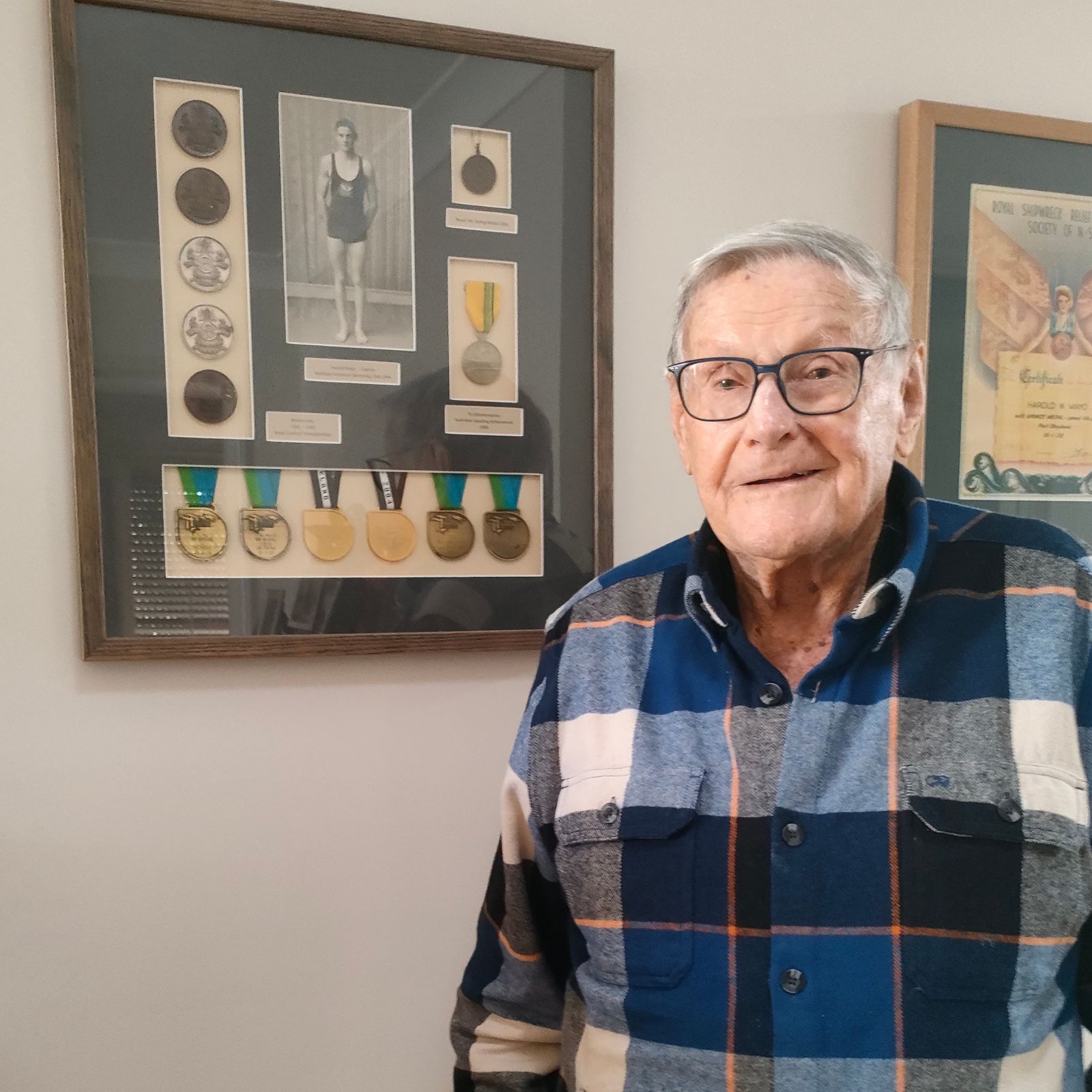 Harold posing against a frame mounted on the wall with his medals